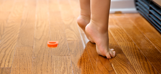 Children's feet tiptoeing on hardwood floor
