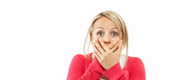 Woman in pink sweater covering mouth in surprise